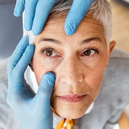A person undergoing a hair or scalp treatment, with gloved hands carefully working on the head.